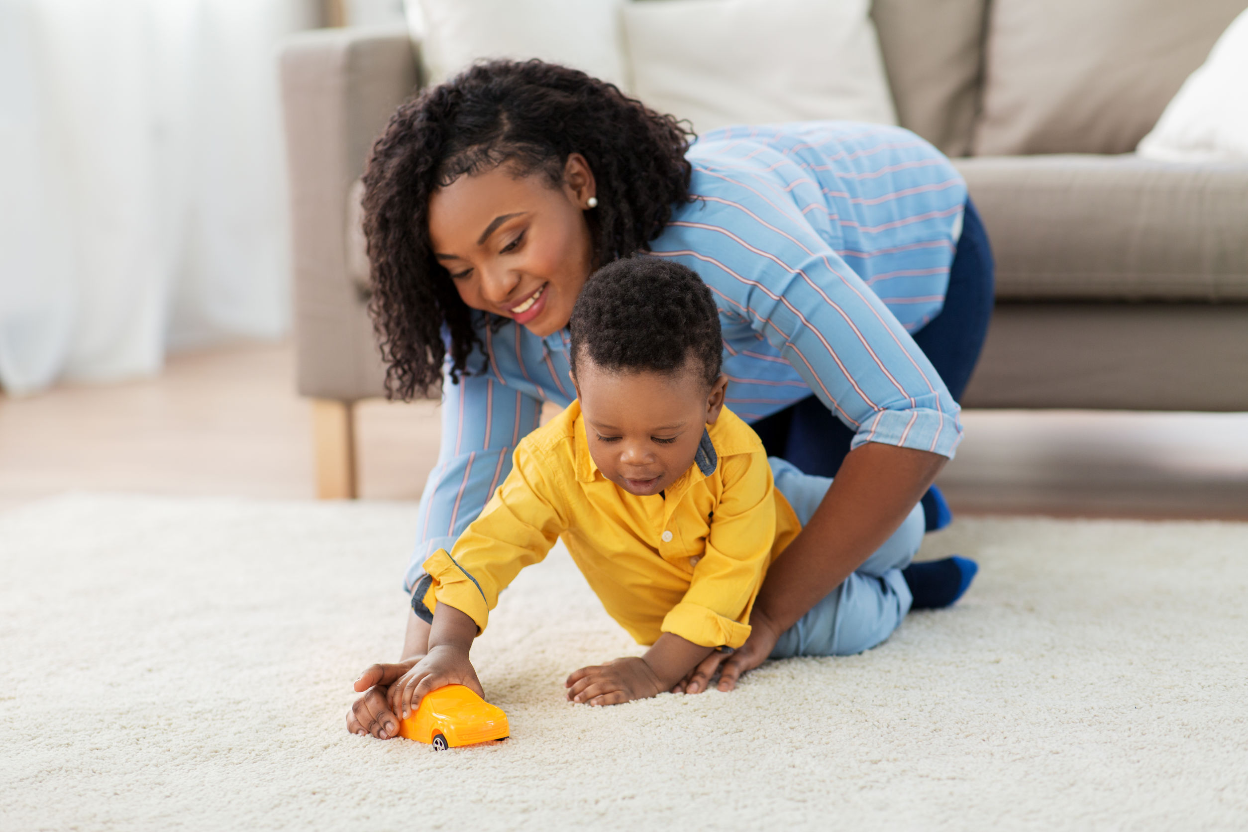 mother and baby playing with toy car at home